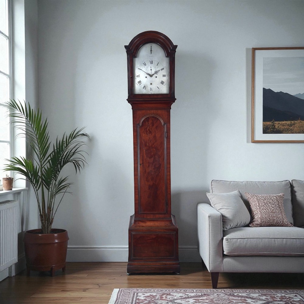 An 18th-century Georgian flame mahogany longcase clock featuring an arched hood, silvered dial with Roman numerals, and a tall wooden trunk. View III