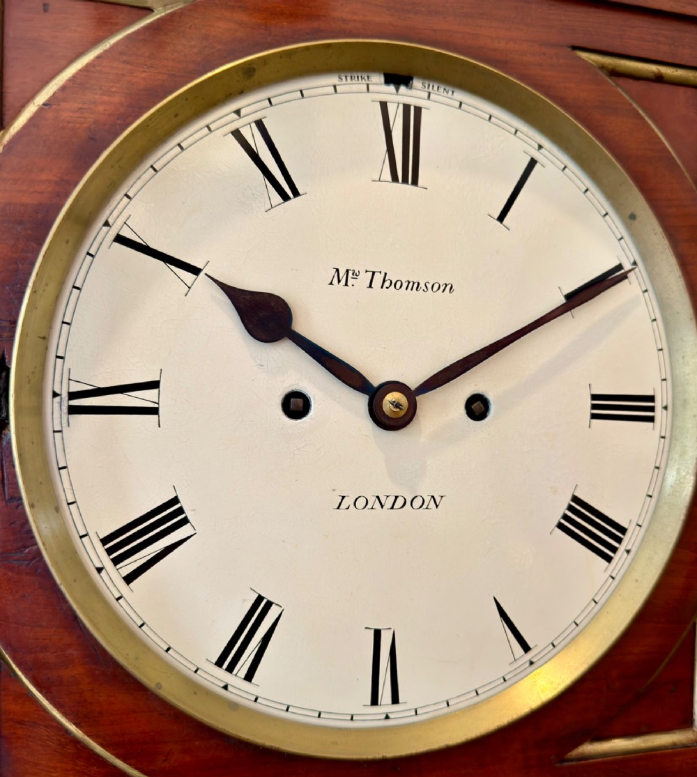A Regency mahogany bracket clock featuring a cream dial with Roman numerals signed Thomson London, set within a brass-inlaid wooden case. View III
