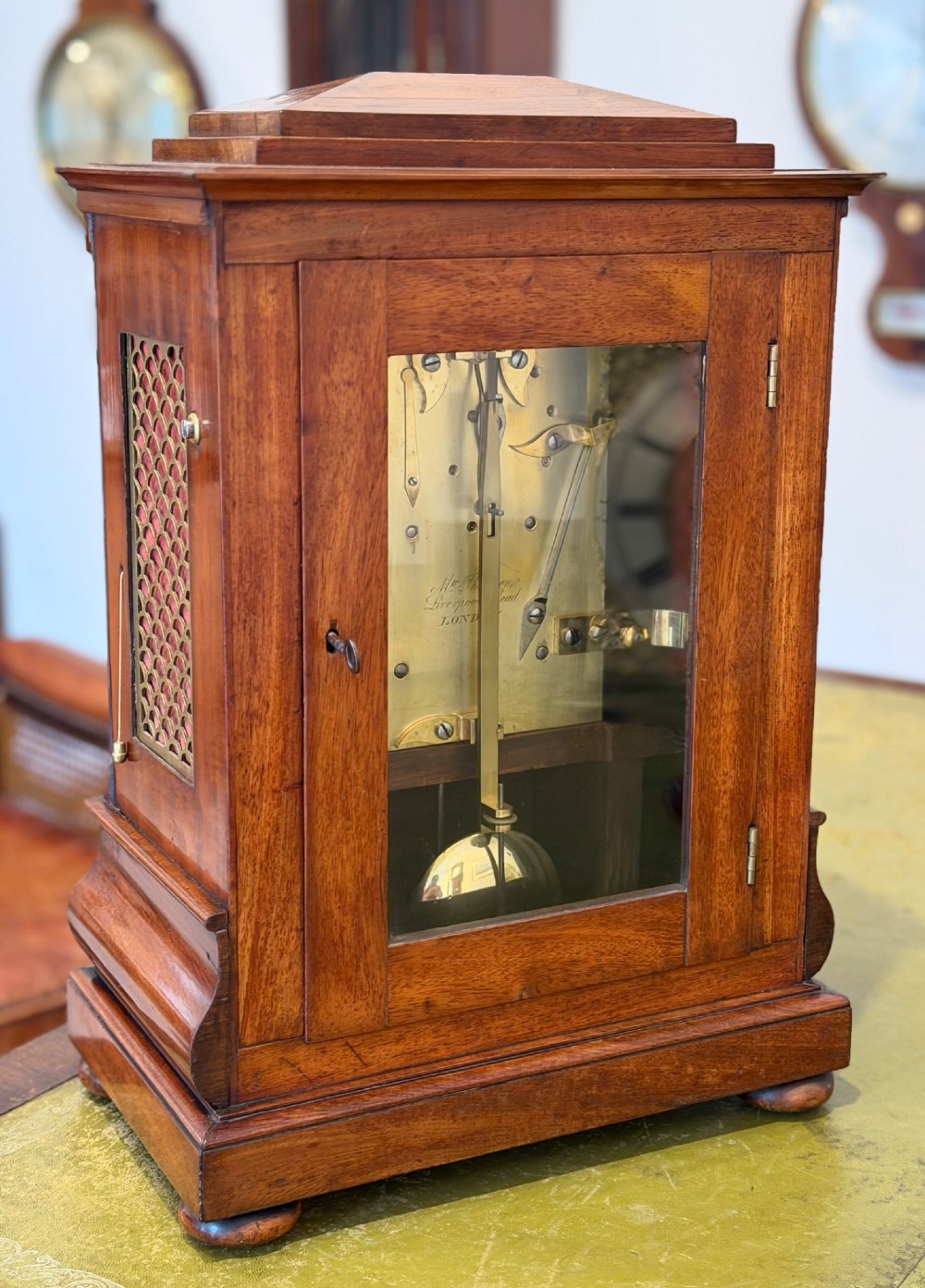 A Regency mahogany bracket clock featuring a cream dial with Roman numerals signed Thomson London, set within a brass-inlaid wooden case. View IV
