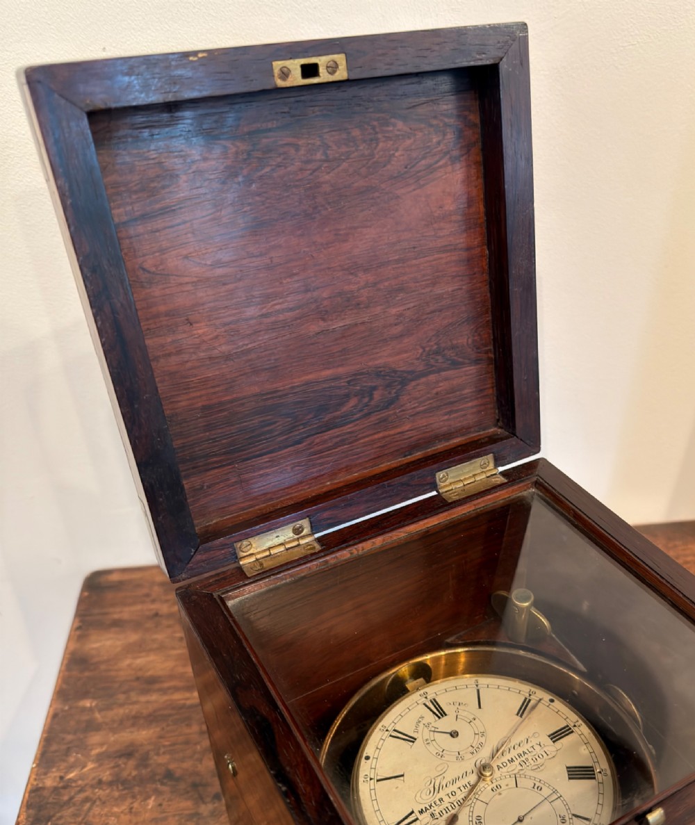 A Thomas Mercer marine chronometer with a silvered dial and brass gimbal mechanism set inside an open mahogany box. View V