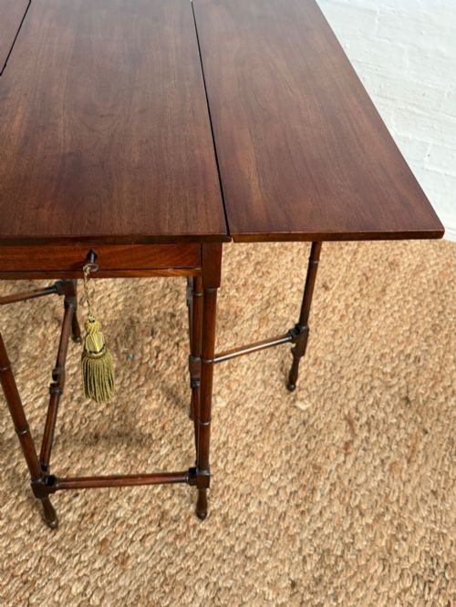 fig 4. An Edwardian solid dark mahogany drop-leaf side table featuring turned faux-bamboo legs, a central drawer with a key, and a double-tier stretcher base.