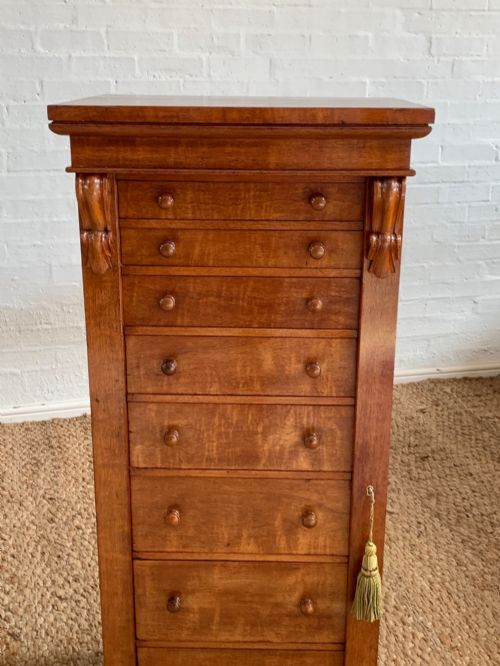 fig 2. A tall Victorian figured mahogany Wellington chest with eight graduated drawers, turned wooden knobs, carved corbels, and a hinged side locking bar.