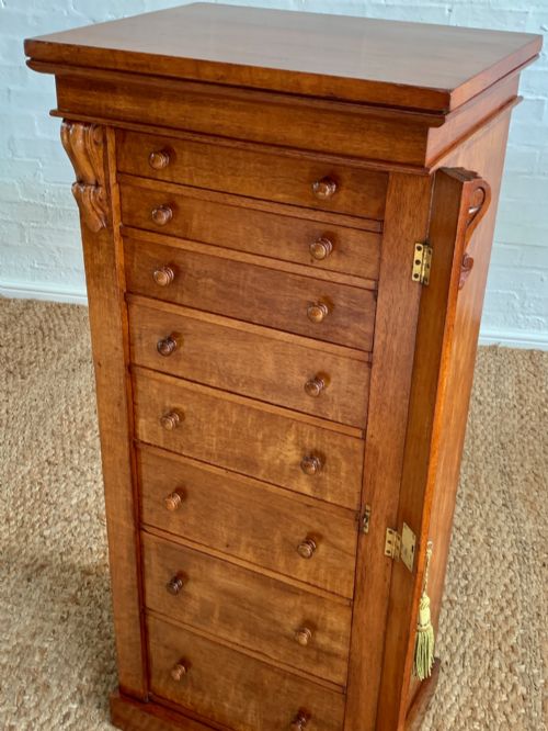 fig 3. A tall Victorian figured mahogany Wellington chest with eight graduated drawers, turned wooden knobs, carved corbels, and a hinged side locking bar.