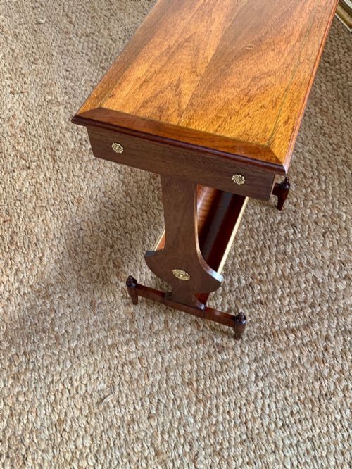 fig 2. A dark mahogany Canterbury side table featuring a rectangular top, a single shallow drawer with brass knobs, and a lower V-shaped magazine trough supported on shaped uprights.