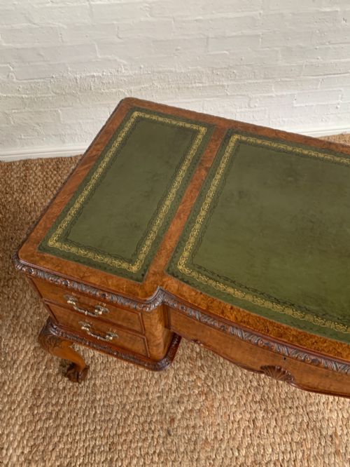 fig 2. A burr walnut kneehole writing desk with four drawers, carved cabriole legs with claw and ball feet, and a green leather writing surface.