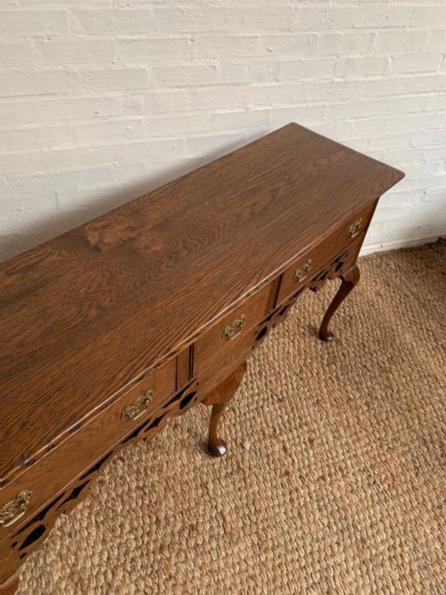 fig 2. An Edwardian oak dresser base featuring three drawers with brass handles, a decorative pierced fretwork apron, and four cabriole legs terminating in pad feet.