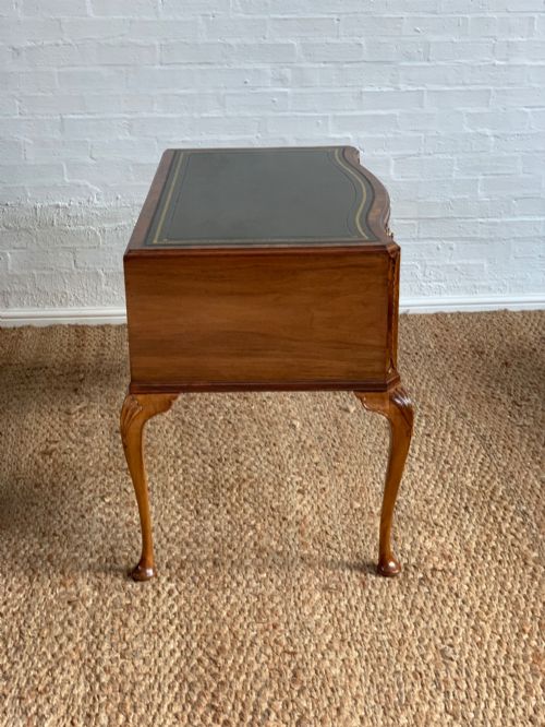fig 2. An early 20th-century burr walnut writing desk featuring an inset leather top, kneehole drawer arrangement, brass drop handles, and cabriole legs.