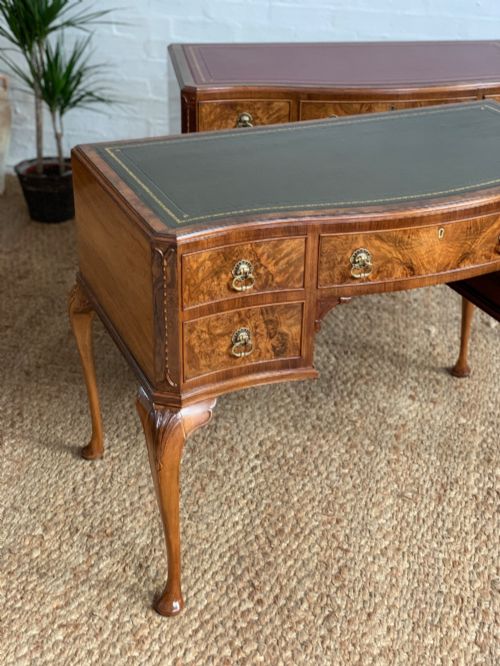 fig 3. An early 20th-century burr walnut writing desk featuring an inset leather top, kneehole drawer arrangement, brass drop handles, and cabriole legs.