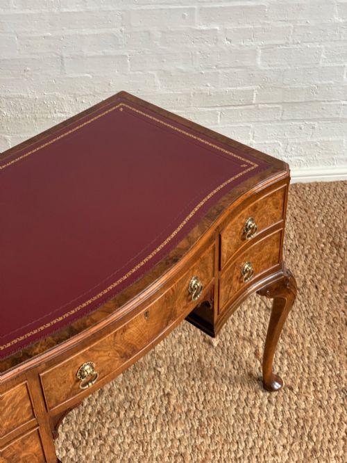 fig 2. An early 20th-century burr walnut writing desk featuring five drawers with brass handles, carved cabriole legs, and a fitted kneehole.