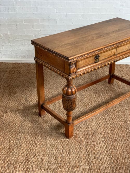 fig 1. A 1920s carved oak side serving table with two drawers, brass handles, carved bulbous front legs, and a lower stretcher frame.