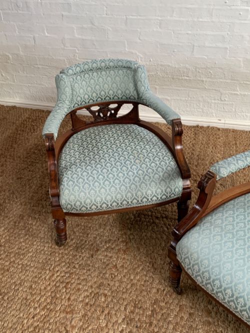 fig 2. A pair of Edwardian walnut tub armchairs with pale blue patterned upholstery, turned front legs, and castors.