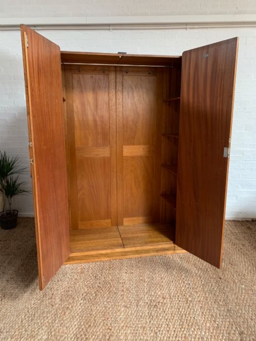 fig 3. An Art Deco double wardrobe crafted from figured burr walnut veneer with rounded top edges, vertical wooden handles, and a stepped plinth base.