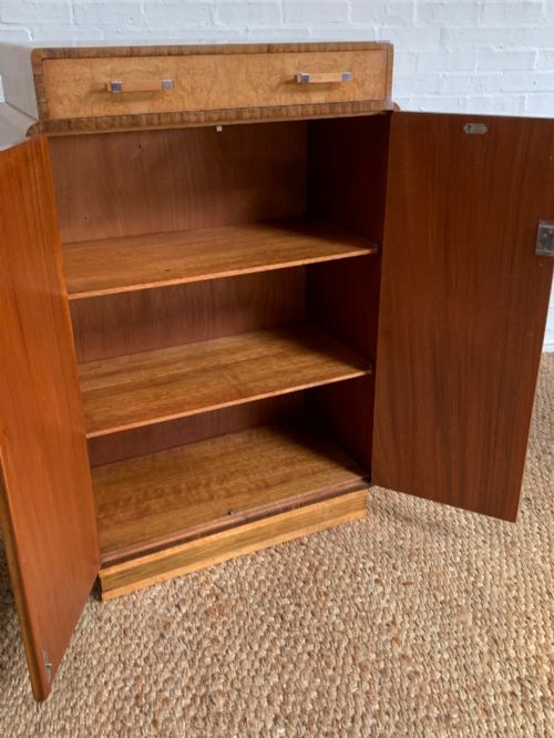 fig 2. An Art Deco tallboy made from book-matched burr walnut, featuring a top drawer over a two-door cabinet on a stepped plinth base.