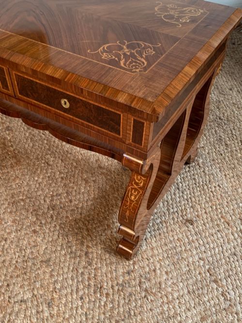 fig 5. A rectangular walnut writing desk featuring decorative corner marquetry, three frieze drawers with brass pulls, curved lyre-shaped legs, and a shaped central stretcher.