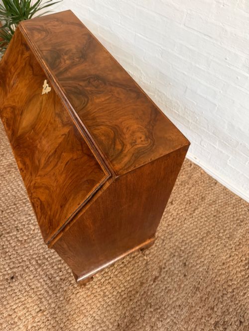 fig 1. A Georgian period figured walnut bureau featuring a slant front flap above four graduated drawers with brass handles, resting on bracket feet.