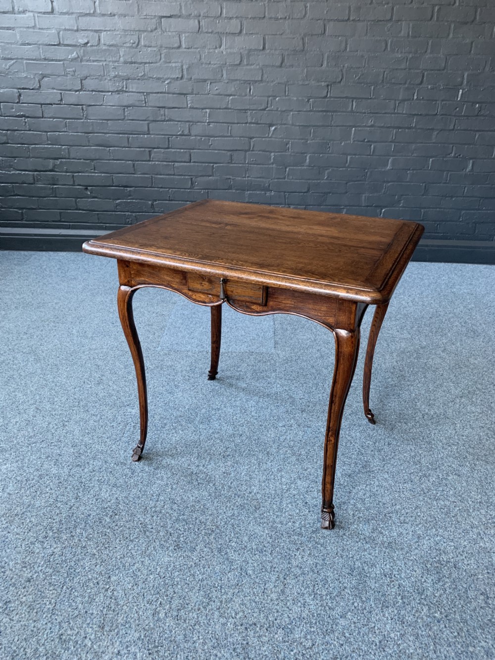 An 18th-century French Provincial timber side table featuring cabriole legs, a single frieze drawer, and a shaped apron.