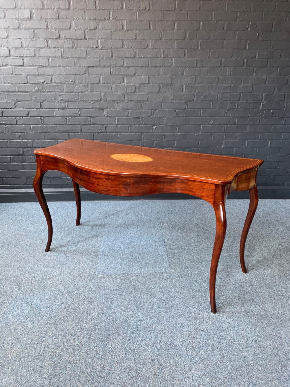 A George III mahogany serpentine side table featuring a central oval marquetry patera and cabriole legs.