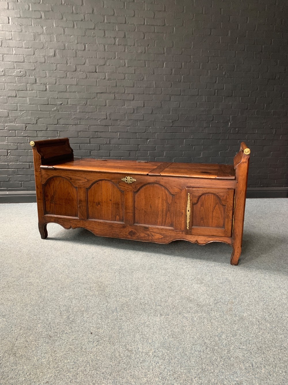 An 18th-century continental oak bench coffer featuring panelled woodwork, hinged lids, and brass hardware.