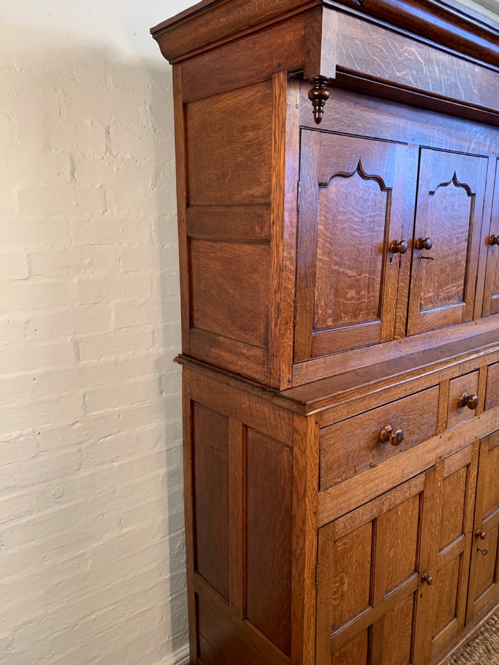A 19th-century two-tier Welsh oak deuddarn cupboard featuring ogee arched panel doors, turned wooden knobs, and a moulded cornice. View II