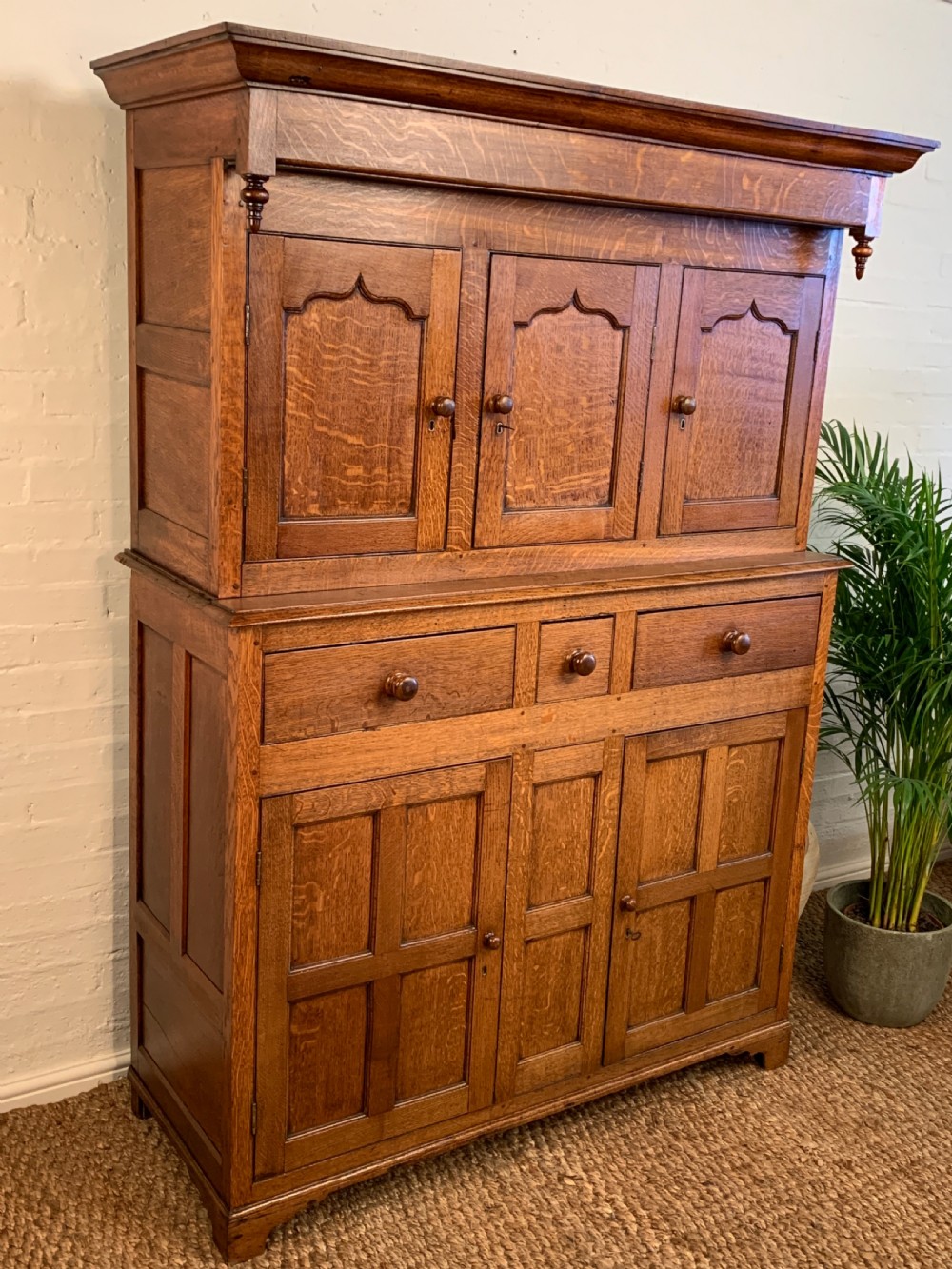 A 19th-century two-tier Welsh oak deuddarn cupboard featuring ogee arched panel doors, turned wooden knobs, and a moulded cornice. View III