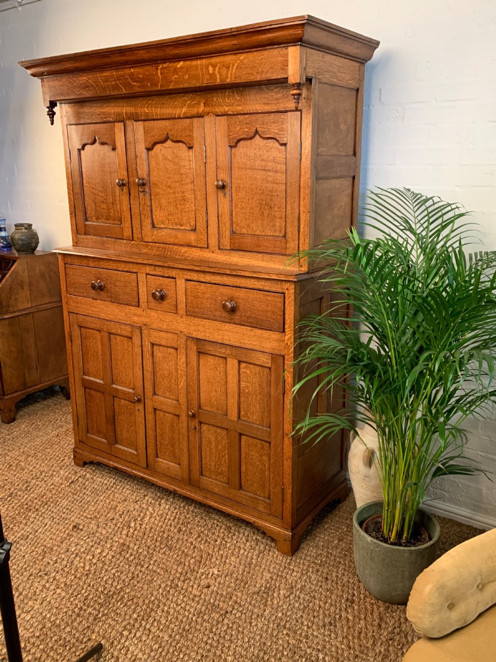 A 19th-century two-tier Welsh oak deuddarn cupboard featuring ogee arched panel doors, turned wooden knobs, and a moulded cornice. View V