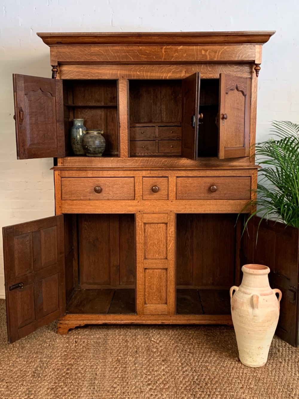 A 19th-century two-tier Welsh oak deuddarn cupboard featuring ogee arched panel doors, turned wooden knobs, and a moulded cornice. View VII