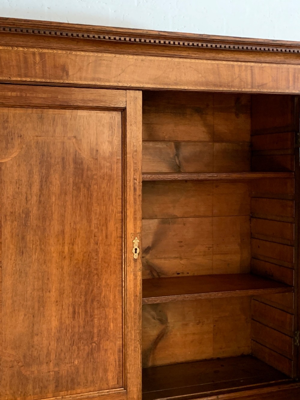A two-stage Georgian oak press cupboard featuring a double-door upper cabinet mounted over a chest of drawers with oval brass handles. View VIII