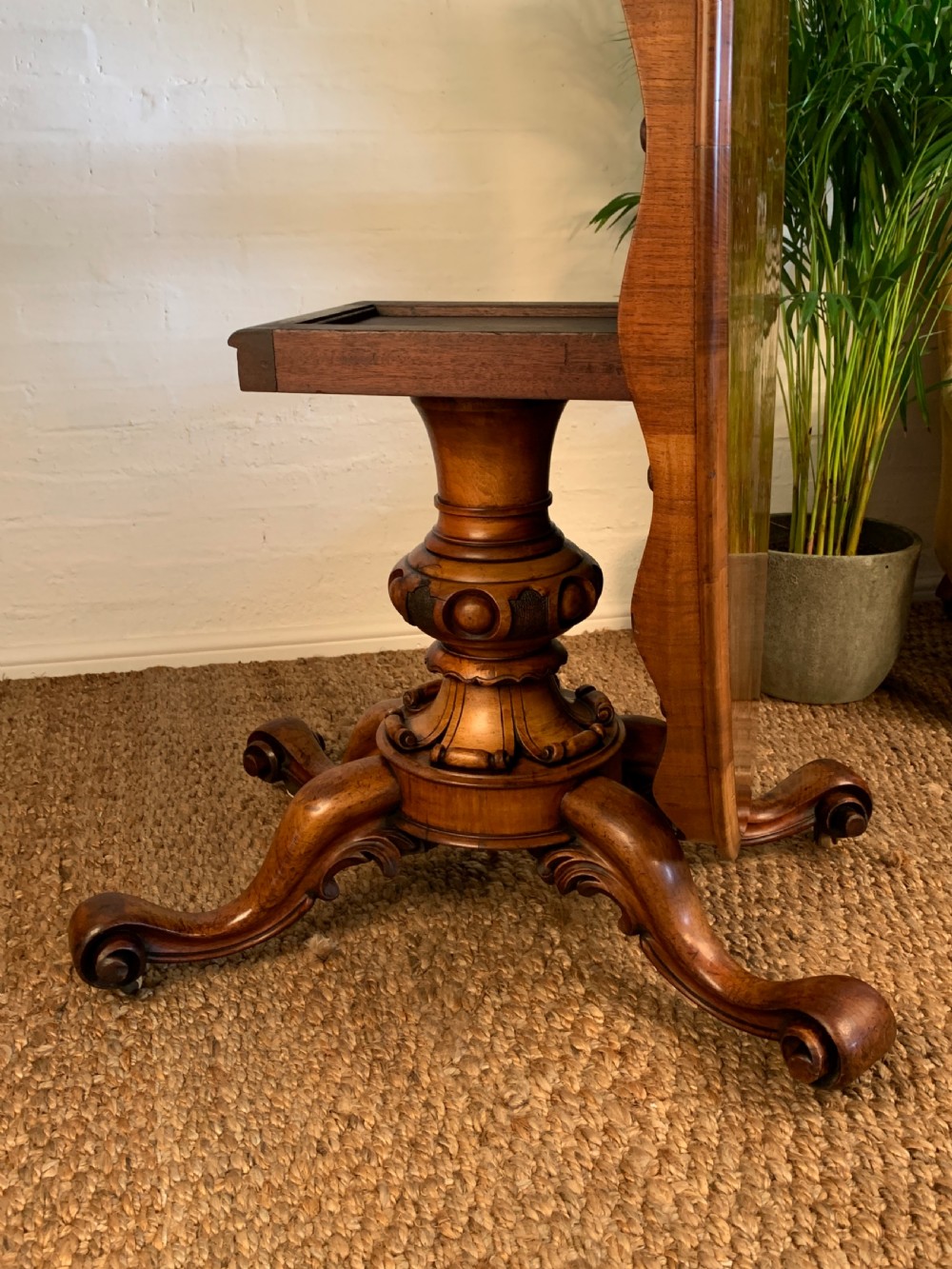 An antique Victorian oval tilt-top centre table made of highly figured burr walnut veneer with a carved pedestal base on castors. View II