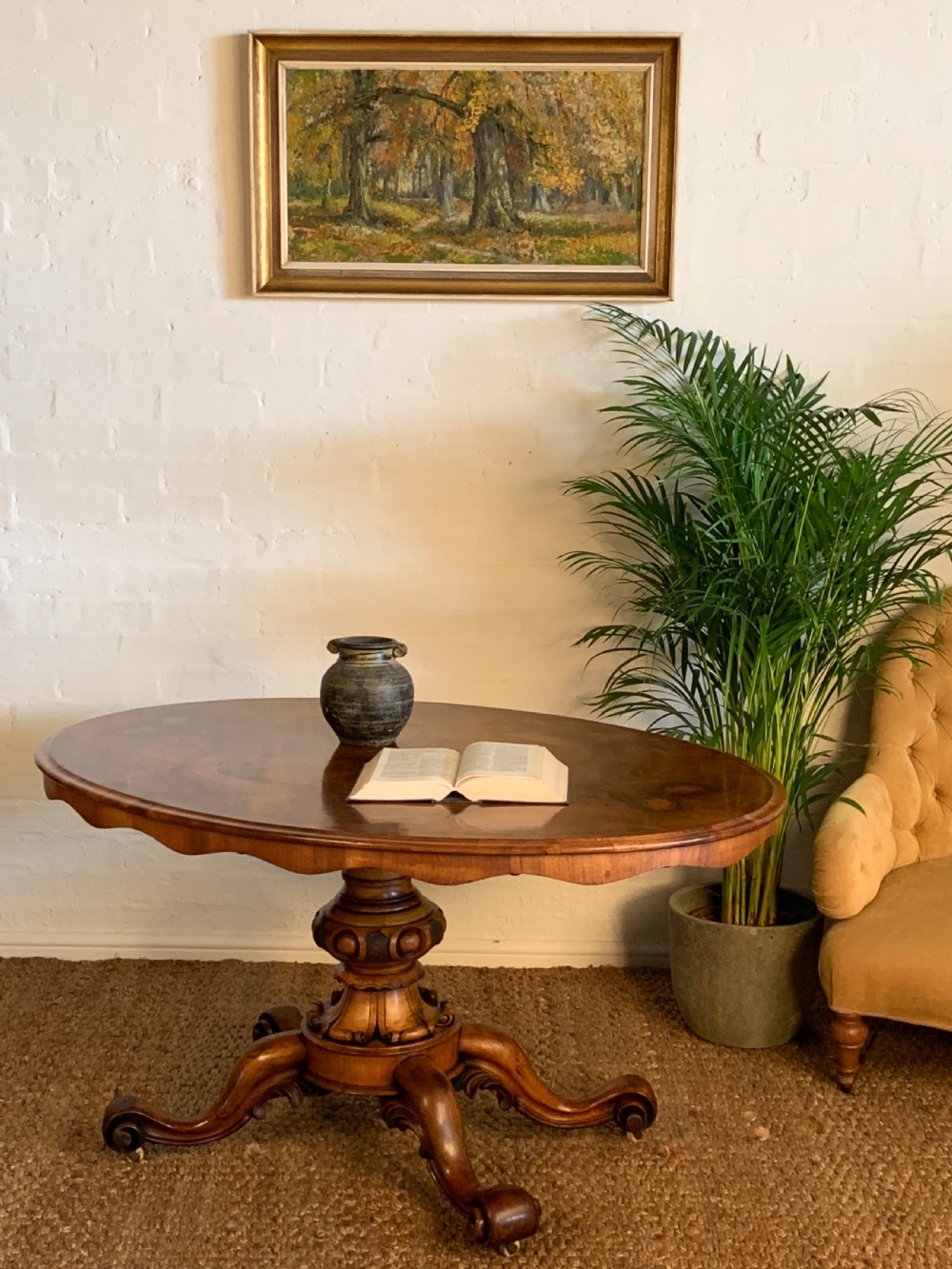 An antique Victorian oval tilt-top centre table made of highly figured burr walnut veneer with a carved pedestal base on castors. View VI