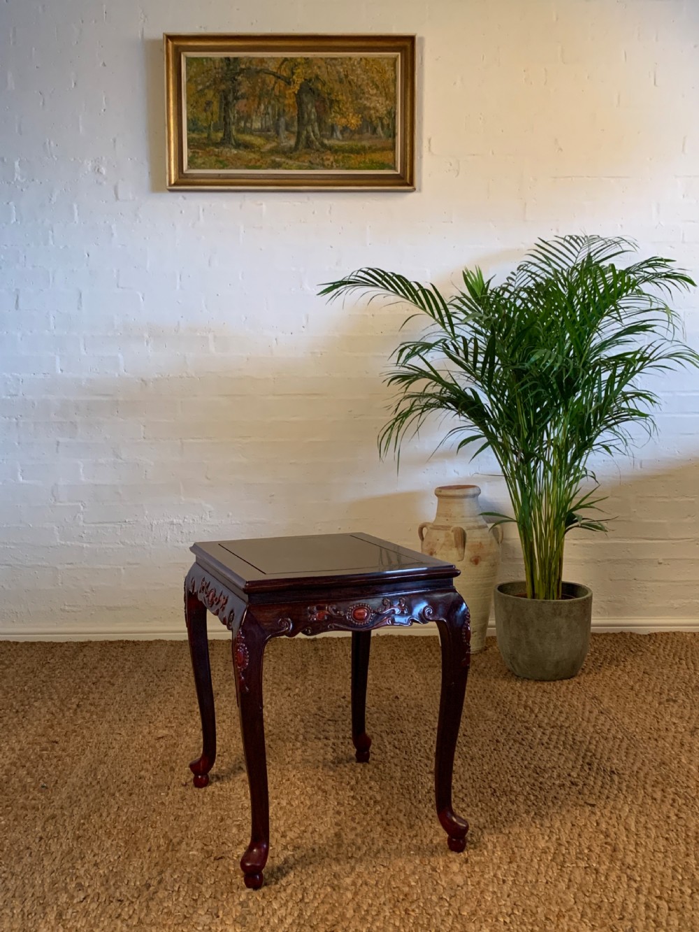 A 19th-century dark reddish-brown Chinese hardwood side table featuring an inset square top, intricately carved apron, and cabriole legs.