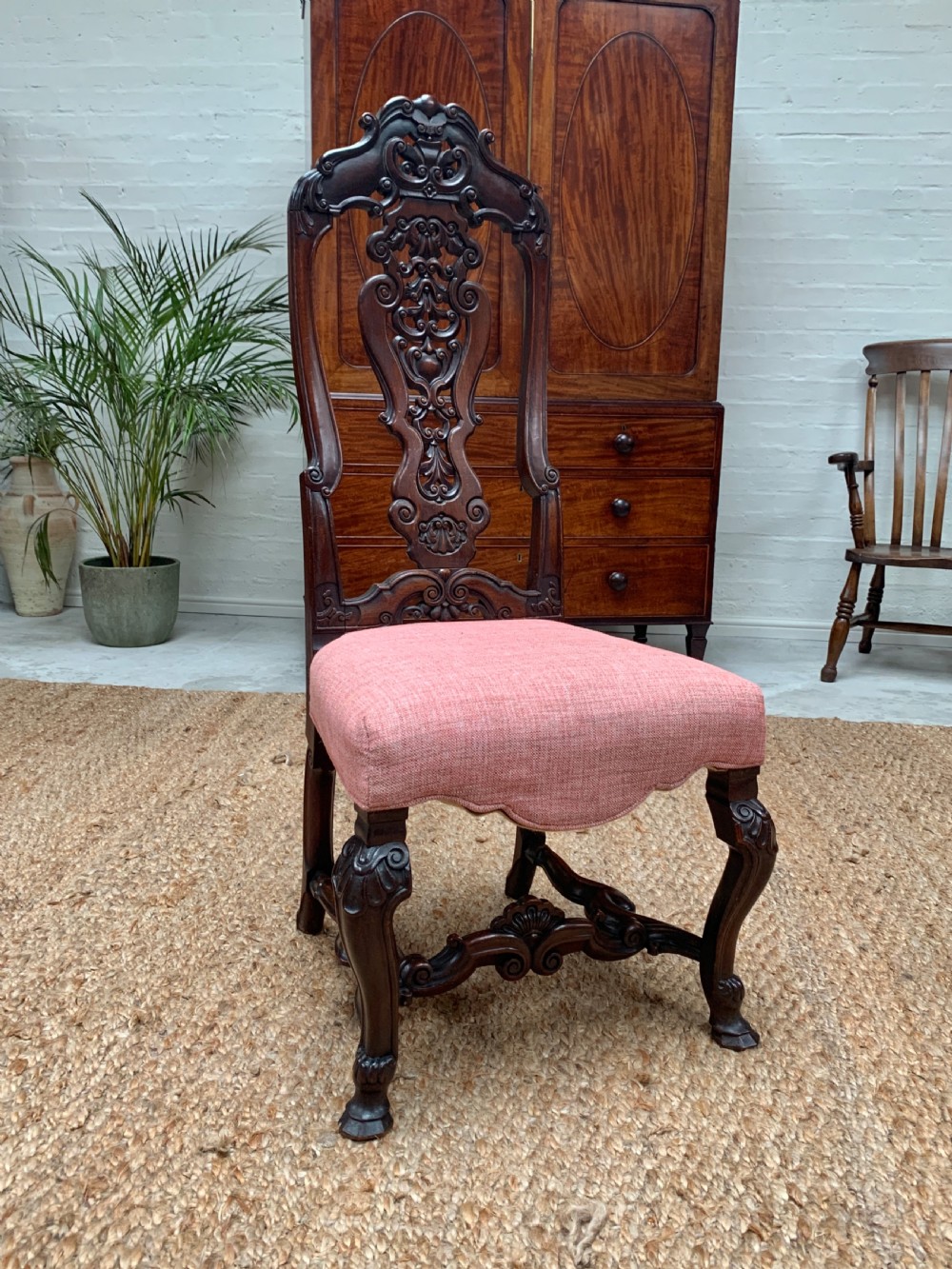 A 19th-century Continental walnut side chair featuring elaborate openwork scrollwork carving, cabriole legs, and a pink upholstered seat.