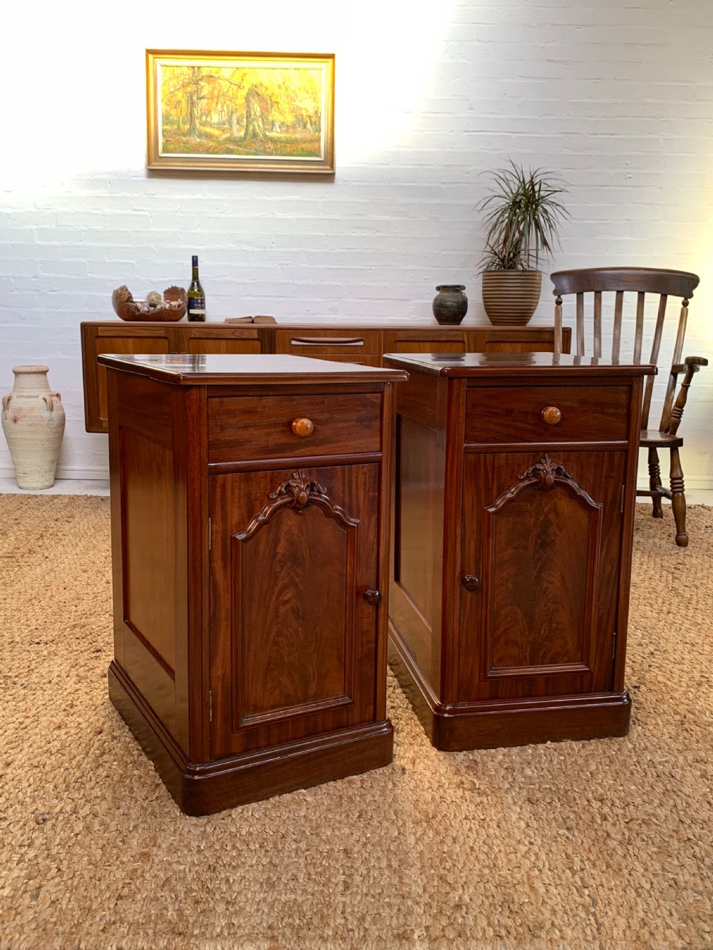 A pair of Victorian mahogany bedside cabinets featuring single top drawers, arched carved panel cupboard doors, and solid plinth bases.