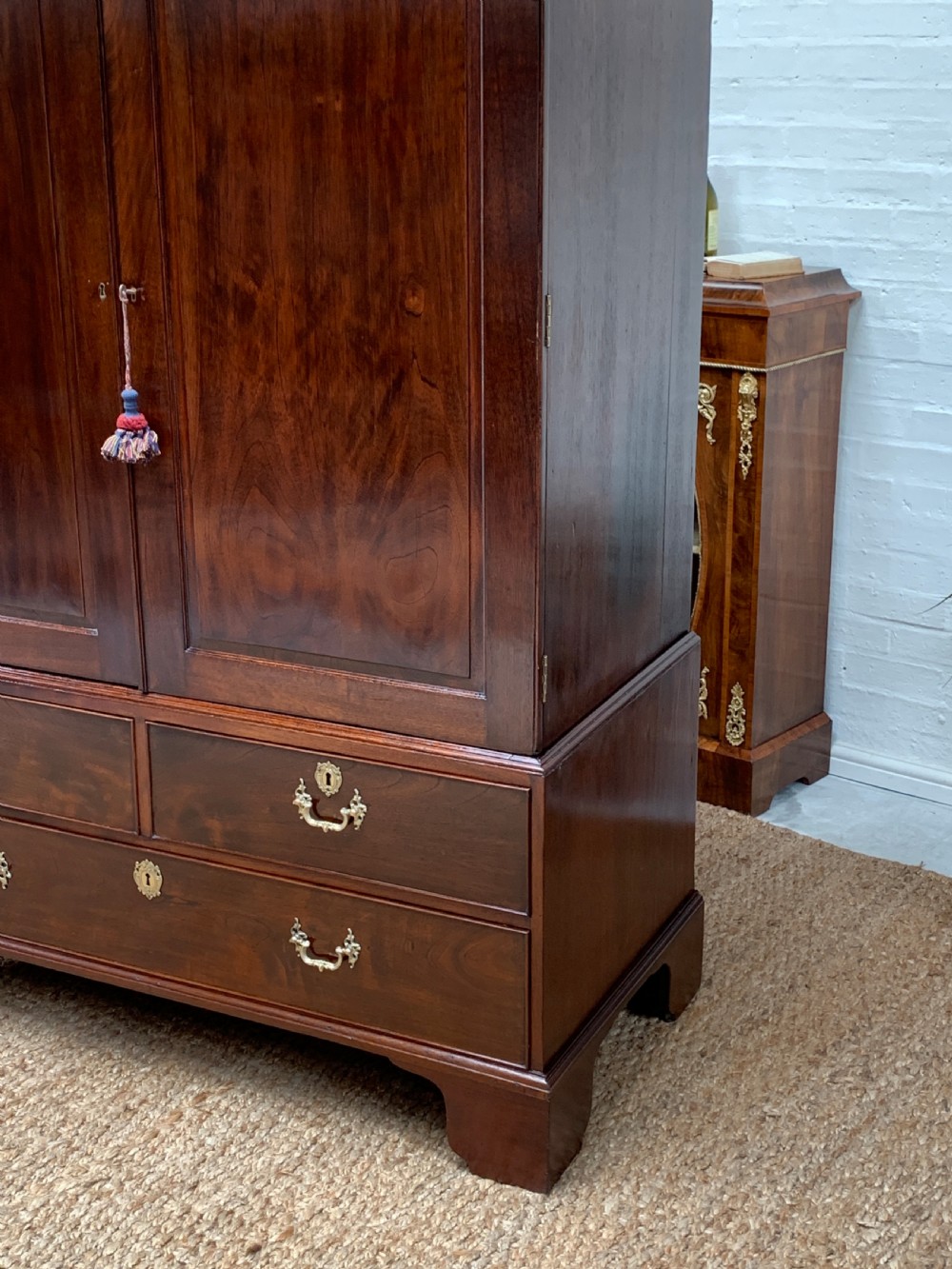 A Georgian dark mahogany linen press featuring two large flame mahogany panelled doors with rosewood crossbanding above two wide drawers with oval brass handles. View III