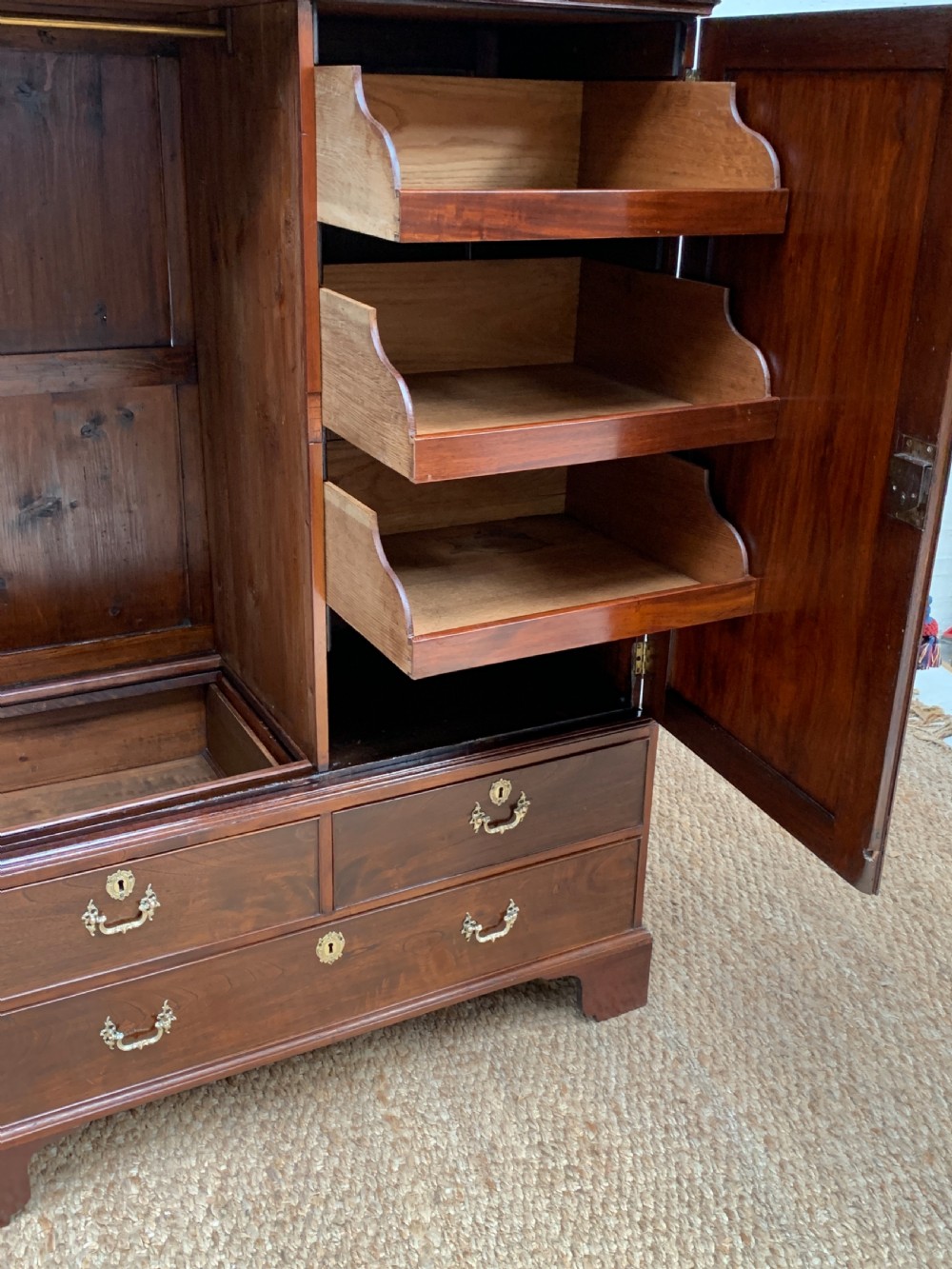 A Georgian dark mahogany linen press featuring two large flame mahogany panelled doors with rosewood crossbanding above two wide drawers with oval brass handles. View VIII