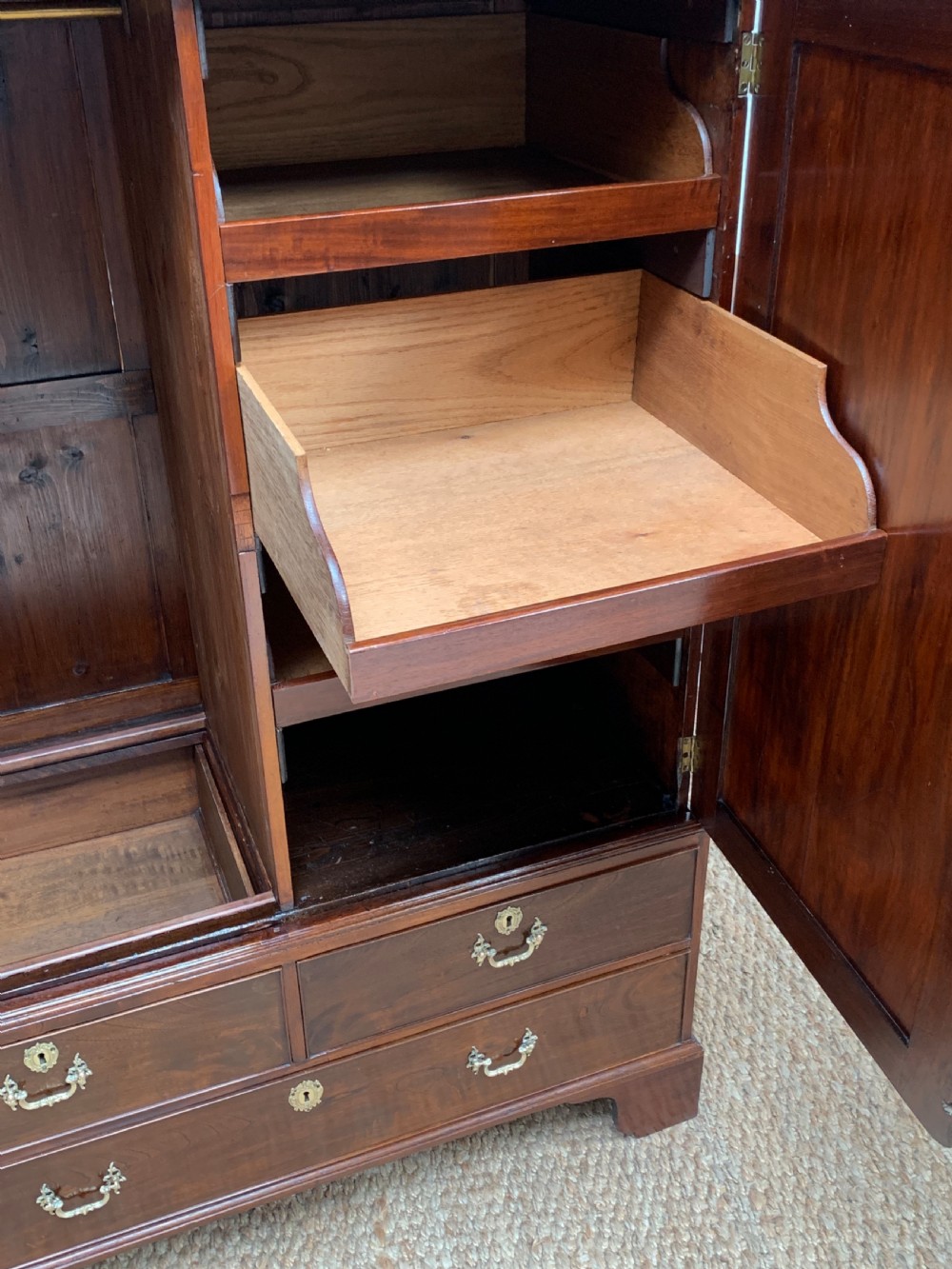 A Georgian dark mahogany linen press featuring two large flame mahogany panelled doors with rosewood crossbanding above two wide drawers with oval brass handles. View IX