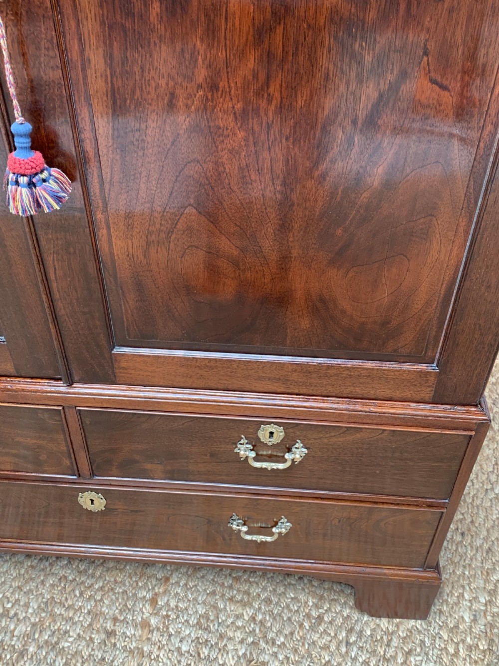 A Georgian dark mahogany linen press featuring two large flame mahogany panelled doors with rosewood crossbanding above two wide drawers with oval brass handles. View XI