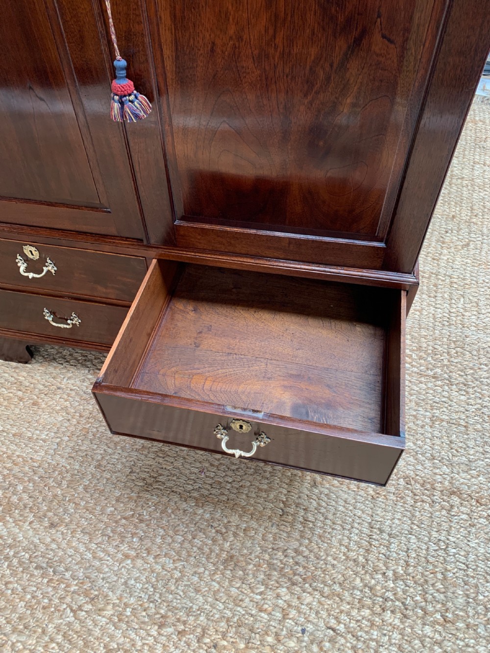 A Georgian dark mahogany linen press featuring two large flame mahogany panelled doors with rosewood crossbanding above two wide drawers with oval brass handles. View XIV