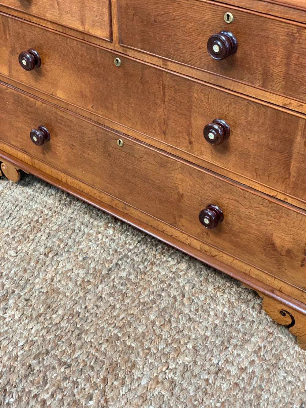 An antique warm brown oak linen press featuring an upper double-door cupboard with arched panels and barley twist columns set over a base with four drawers. View VI