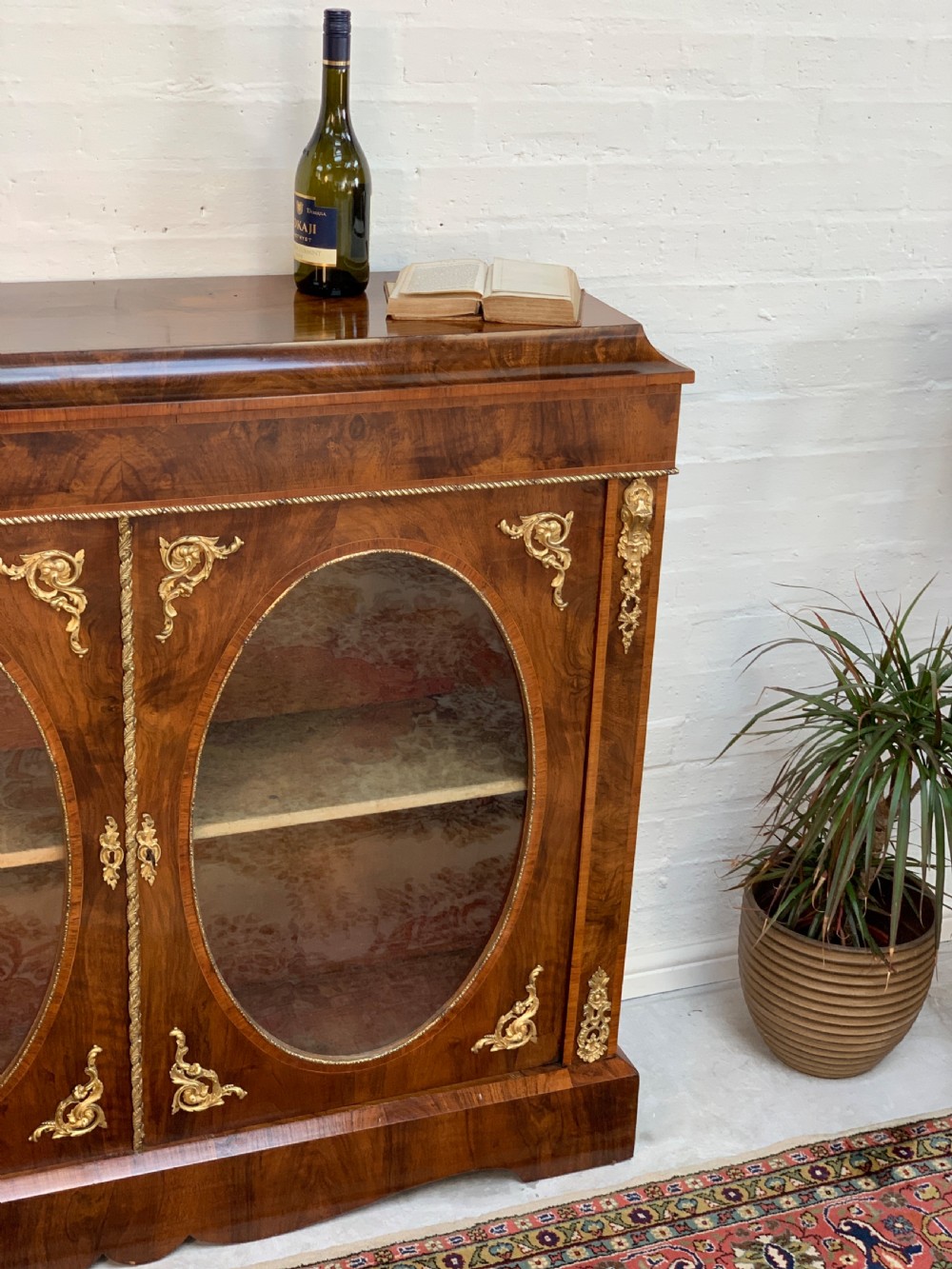 A Victorian double-door pier cabinet featuring figured walnut veneers, oval glass door panels, and decorative brass mounts. View V