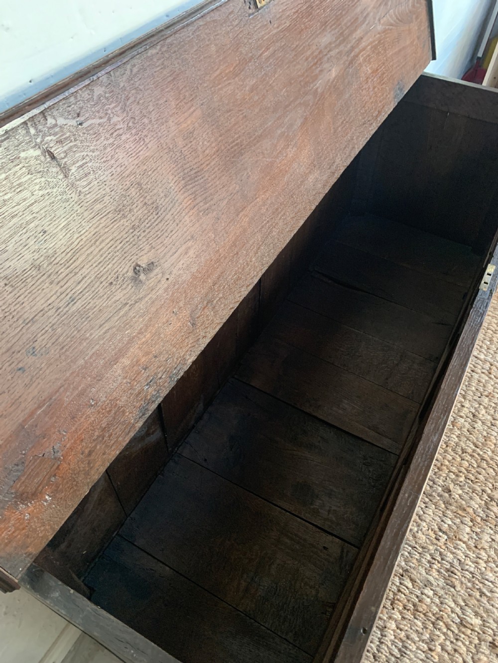 A dark oak mule chest featuring a hinged top, raised arched panels, multiple lower drawers, and brass batwing handles. View IX