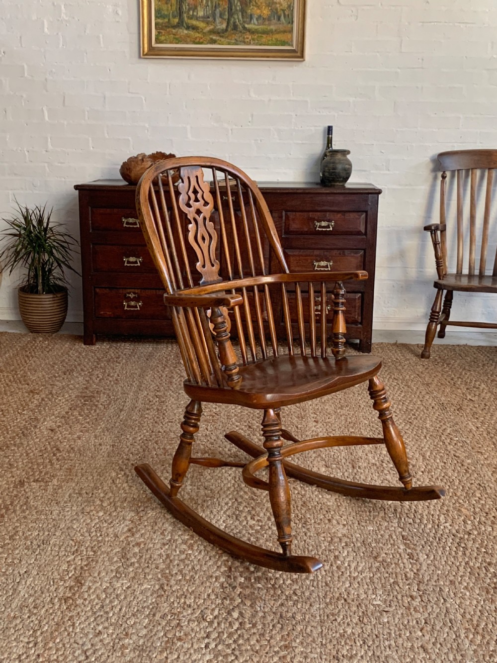 A nineteenth-century country-style Windsor rocking chair featuring a hoop back, central pierced splat, turned spindles, and shaped armrests on curved wooden rockers.