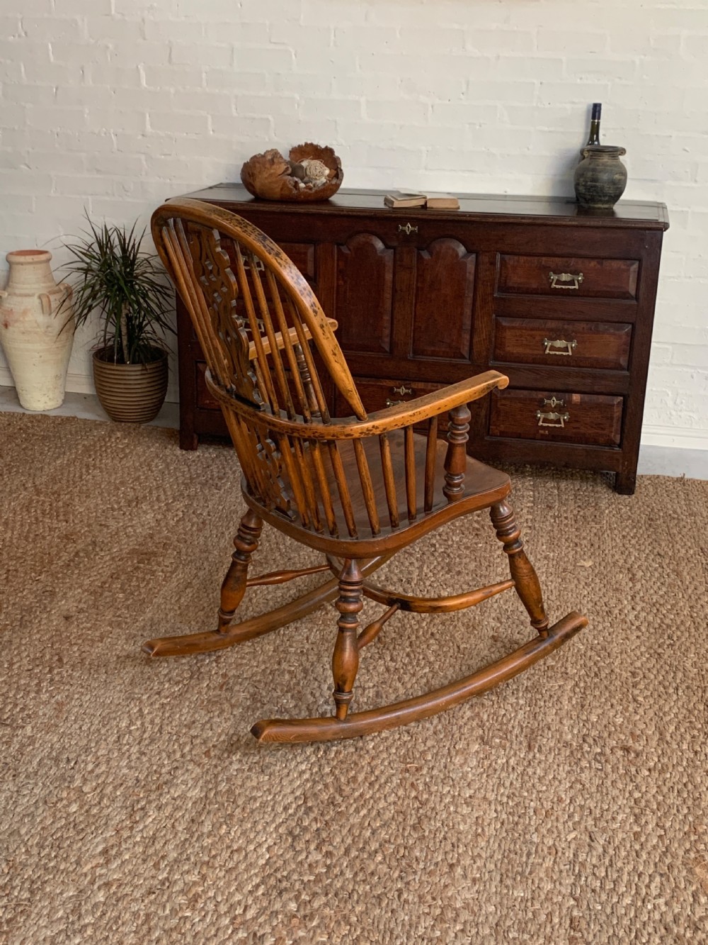 A nineteenth-century country-style Windsor rocking chair featuring a hoop back, central pierced splat, turned spindles, and shaped armrests on curved wooden rockers. View III