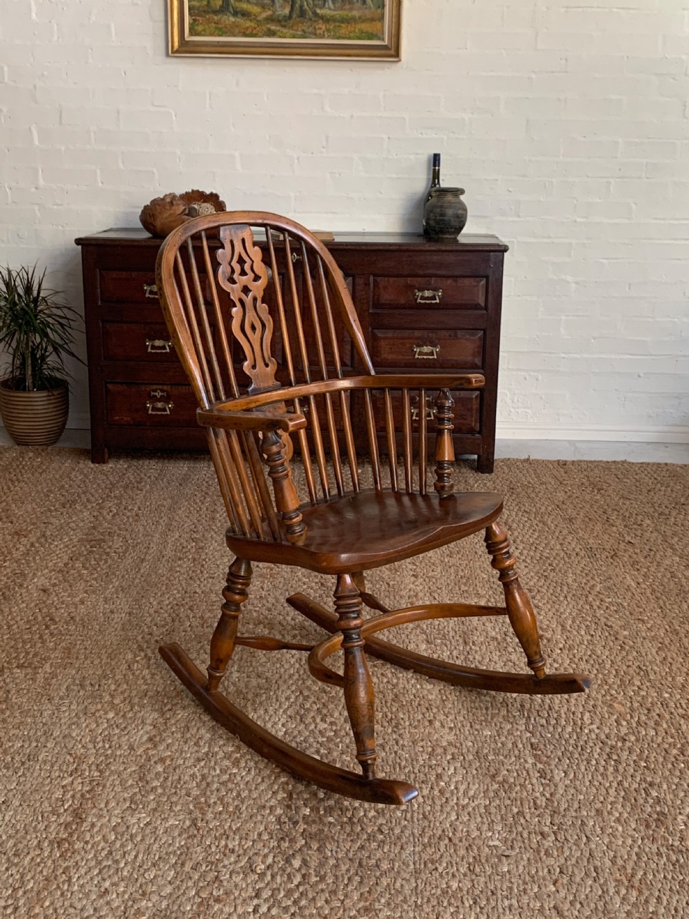 A nineteenth-century country-style Windsor rocking chair featuring a hoop back, central pierced splat, turned spindles, and shaped armrests on curved wooden rockers. View V