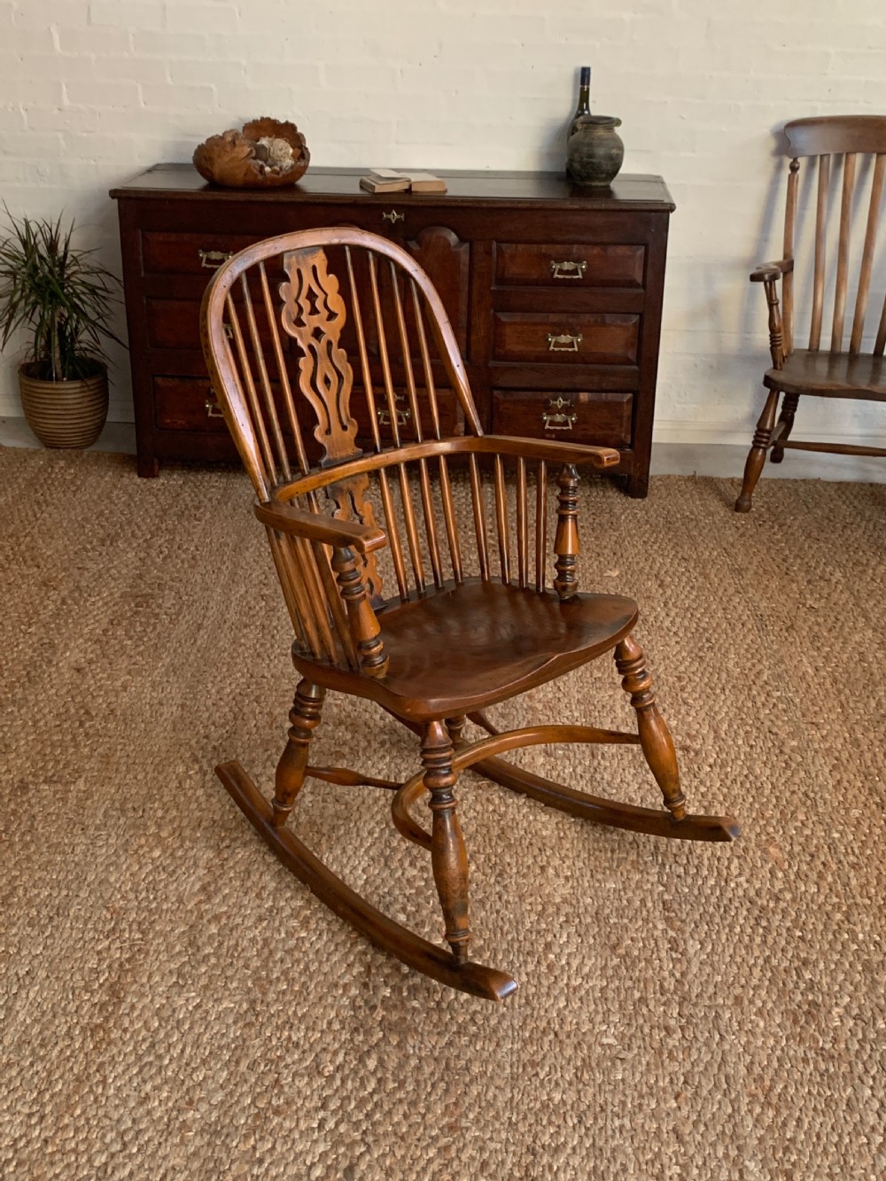 A nineteenth-century country-style Windsor rocking chair featuring a hoop back, central pierced splat, turned spindles, and shaped armrests on curved wooden rockers. View VI