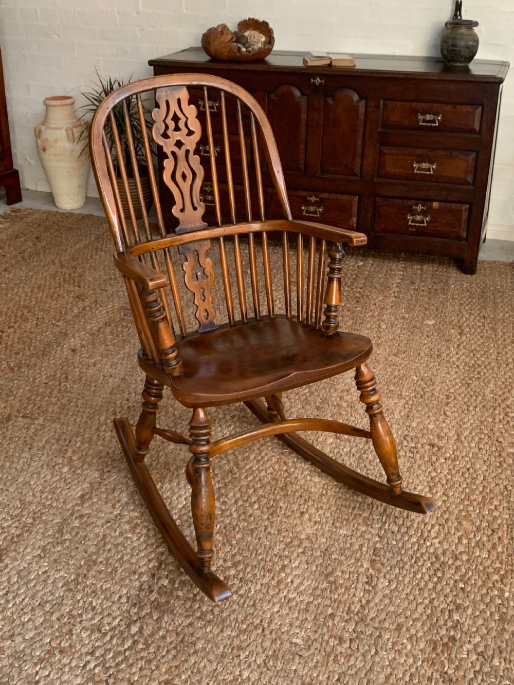 A nineteenth-century country-style Windsor rocking chair featuring a hoop back, central pierced splat, turned spindles, and shaped armrests on curved wooden rockers. View VII