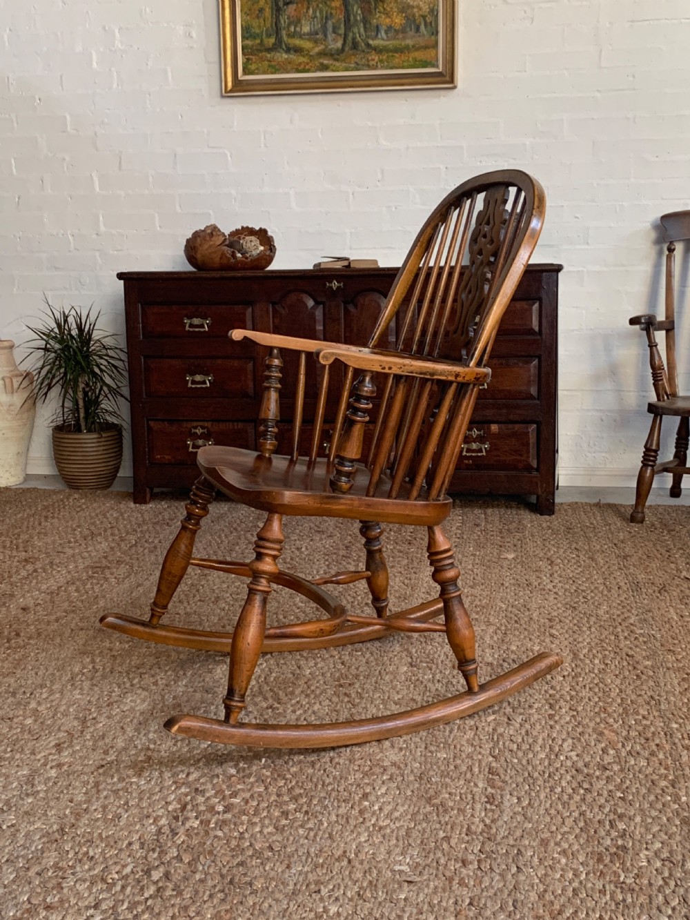 A nineteenth-century country-style Windsor rocking chair featuring a hoop back, central pierced splat, turned spindles, and shaped armrests on curved wooden rockers. View XI