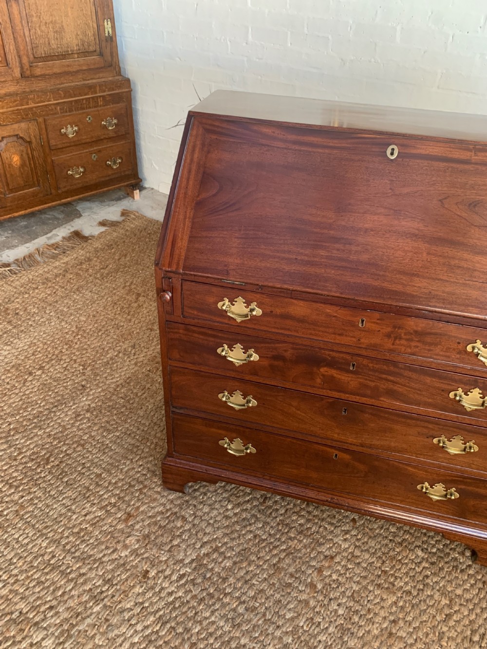 A Georgian mahogany slant-front writing bureau featuring four graduated drawers with brass batwing handles and bracket feet. View IX