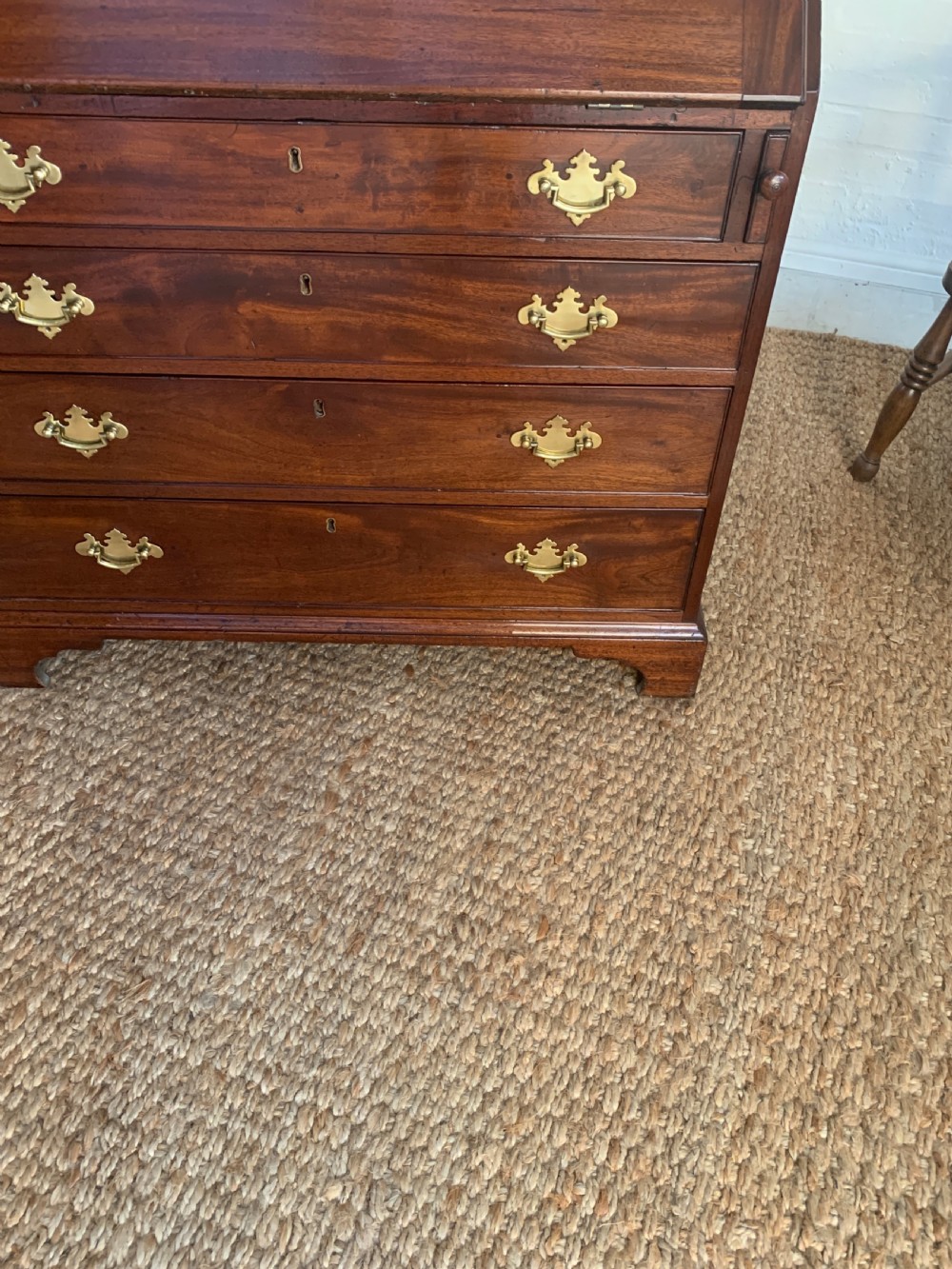 A Georgian mahogany slant-front writing bureau featuring four graduated drawers with brass batwing handles and bracket feet. View X