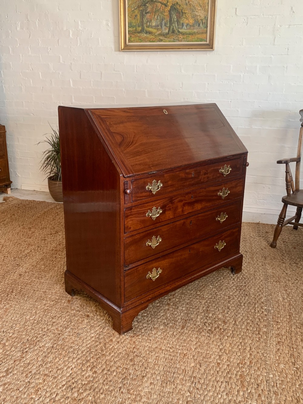 A Georgian mahogany slant-front writing bureau featuring four graduated drawers with brass batwing handles and bracket feet. View XV