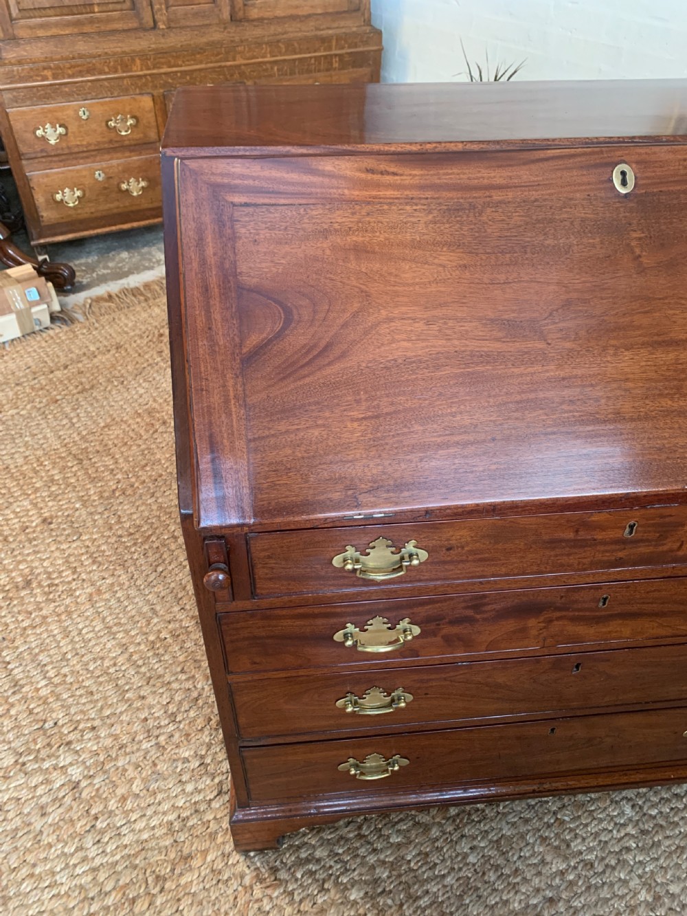 A Georgian mahogany slant-front writing bureau featuring four graduated drawers with brass batwing handles and bracket feet. View XVII